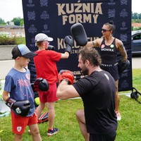 Na zdjęciu dwójka boksujących dzieci wraz z instruktorami