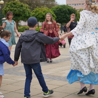 Na zdjęciu taniec w kole - mieszkańcy i panie w sukniech z epoki