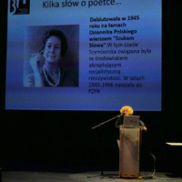 Na zdjęciu osoba przemawiająca na scenie, w tle slajd z informacjami o Wisławie Szymborskiej