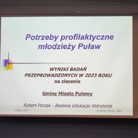 Slajd przedstawiający tytuł i nazwę badań: Potrzeby profilaktyczne młodzieży Puław. Wyniki badań przeprowadzonych w 2023 roku na zlecenie Gminy Miasto Puławy. Robert Porzak. Badania, Edukacja, Wdrożenia.